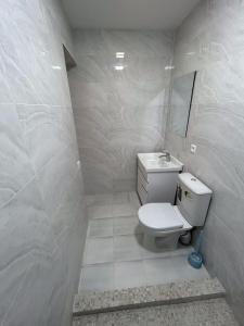 a white bathroom with a toilet and a sink at "Lime" Aparthotel in Bukhara