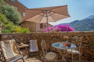 eine Terrasse mit einem Tisch, Stühlen und einem Sonnenschirm in der Unterkunft A StALLA MAISON DE VACANCES 6 PERSONNES in Muro