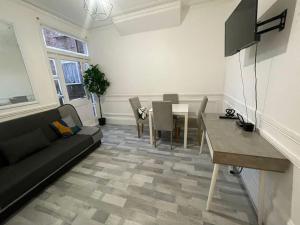 een woonkamer met een bank en een eettafel bij Ground Floor 2 Bed Flat with Garden North London in Londen