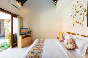 a bedroom with a bed and a television in it at Kubal Villa and Living Seminyak in Canggu