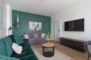 a living room with a green couch and a flat screen tv at Urban Garden Hetmańska 3 in Poznań