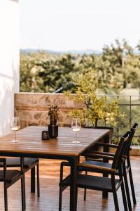 two wine glasses sitting on a wooden table on a patio at Vina Kobal, Kobal Family Estate in Štanjel