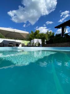 una gran piscina de agua con sombrilla y sillas en Grigliata Motel and Pool en Glevakha