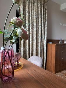 a vase with pink flowers sitting on a wooden table at Grigliata Motel and Pool in Glevakha