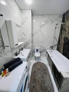 ein weißes Bad mit einem Waschbecken und einem WC in der Unterkunft Новый Люкс жк Сириус в центре Алматы in Almaty