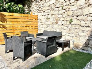 a patio with chairs and tables and a stone wall at La Maison d'Elisa in Les Baux-de-Provence