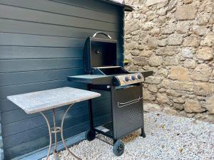 een barbecue met een tafel naast een muur bij La Maison d'Elisa in Les Baux-de-Provence