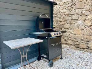 a barbecue grill with a table next to a wall at La Maison d'Elisa in Les Baux-de-Provence