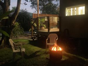 a backyard with two chairs and a fire in the yard at Beach House with spa among the trees Coolum Beach in Coolum Beach