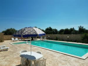 einen Pool mit Sonnenschirm, Tisch und Stühlen in der Unterkunft Villa Corradina in Floridia