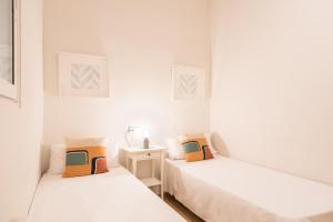 two beds in a room with white walls at Eixample8 in Barcelona