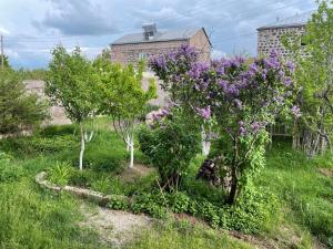 a garden with trees and purple flowers in front of a house at ElMar Guesthouse in Sevan