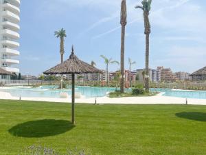 een resort met een zwembad en een parasol in het gras bij Global Properties, Apartamento para 6 personas con terraza in Canet de Berenguer