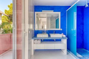 a blue bathroom with two sinks and a mirror at The Pink Elephant Hotel in Sant Feliu de Guíxols