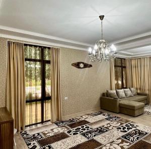 ein Wohnzimmer mit einem Sofa und einem Kronleuchter in der Unterkunft Сдается коттедж на берегу озера Иссык Куль in Chon-Sary-Oy