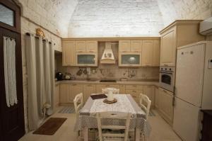 une cuisine avec une table et un réfrigérateur blanc dans l'établissement Locorotondo Stone House, à Locorotondo