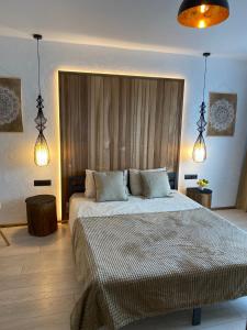 a bedroom with a large bed and two lights at Apartamenti Ezera Pērle in Alūksne