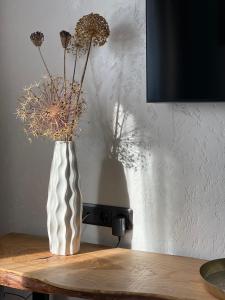 a white vase with dried flowers on a table at Apartamenti Ezera Pērle in Alūksne