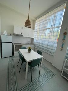 a kitchen with a table and chairs and a refrigerator at A 2 passi dal mare - grazioso trilocale a Locri in Locri