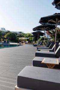 a row of lounge chairs with umbrellas and a pool at Paros Agnanti Resort & Spa in Parikia