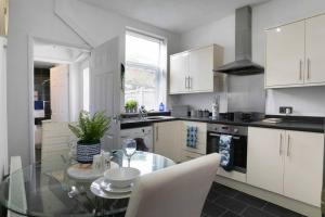 a kitchen with a glass table and white cabinets at *Central 2 bed - Sleeps 5* in Chesterfield