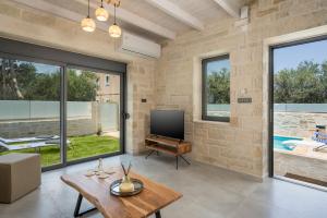 a living room with a flat screen tv and windows at Megalith Villas in Nea Kydonia