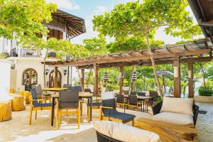 un patio al aire libre con mesas, sillas y árboles en Plaza Mercado 22 at Las Catalinas, en Playa Danta