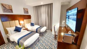a hotel room with two beds and a flat screen tv at Golden dune Hotel - Almalaz in Riyadh