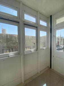 a room with three windows with a view of a city at Cozy 2 bedroom Apartment near Seafront in Il-Gżira
