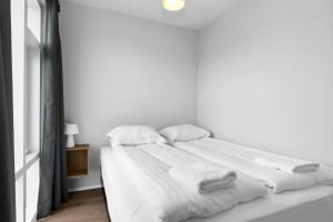 Una cama blanca con sábanas blancas y toallas. en Central Studio Apartment en Reikiavik