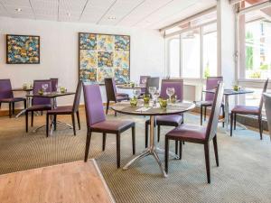 - une salle à manger avec des tables, des chaises et des fenêtres dans l'établissement Novotel Aix-en-Provence Beaumanoir, à Aix-en-Provence