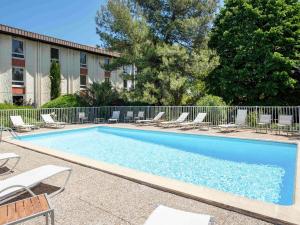 une grande piscine avec des chaises et une clôture dans l'établissement Novotel Aix-en-Provence Beaumanoir, à Aix-en-Provence