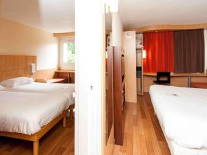 a hotel room with two beds and a red curtain at ibis Avallon in Magny
