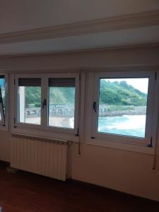 three windows in a room with a view of the water at Haitze in Getaria