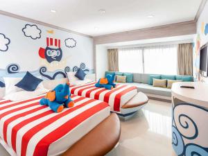 Novotel Phuket Resort في شاطيء باتونغ: غرفة نوم بسريرين يوجد عليها حيوانات محشوة
