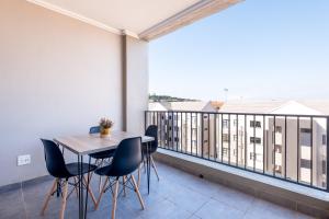 a dining room with a balcony with a table and chairs at Ballito Village Luxury Apartments in Ballito