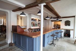 a kitchen with blue cabinets and a bar with stools at Black Lion Hotel in Little Walsingham