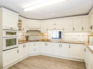 a white kitchen with white cabinets and wooden floors at Oxford House in Minehead