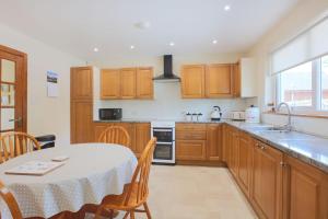 a kitchen with wooden cabinets and a table with a white table cloth at Croftdean in East Barcloy