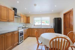 a kitchen with wooden cabinets and a table with chairs at Croftdean in East Barcloy
