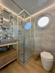 a bathroom with a shower and a toilet and a window at Domki na wodzie - Resort 36 Houseboats in Giżycko