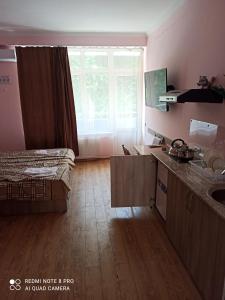 a bedroom with a bed and a kitchen with a window at Hotel Caucase in Tbilisi City