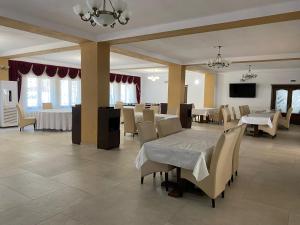 a dining room with a white table and chairs at Pensiunea Perla Codrului in Meziad