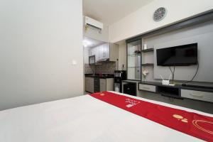 een slaapkamer met een groot wit bed en een televisie bij RedLiving Apartemen Springlake Summarecon - Happy Rooms Tower Elodea with Netflix in Rawabugel