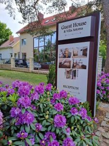 un cartel frente a una casa con flores púrpuras en Guest House & Villa Astoma, en Palanga