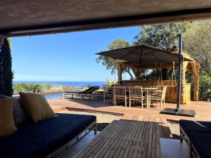 eine Terrasse mit einem Sonnenschirm, einem Tisch und Stühlen in der Unterkunft Magnifique villa avec piscine, splendide vue mer. in Porto-Vecchio