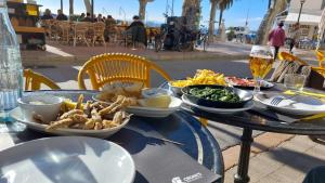 a table with plates of food and a glass of beer at EL GRECO in L'Escala
