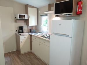 a kitchen with a white refrigerator and a sink at camping bonneval in Jaujac