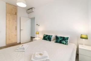 1 dormitorio con 1 cama blanca grande con almohadas verdes en Cabanas Mar 96 en Cabanas de Tavira