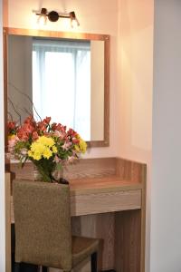 une table avec un vase de fleurs et un miroir dans l'établissement Budapest Hotel, à Sofia